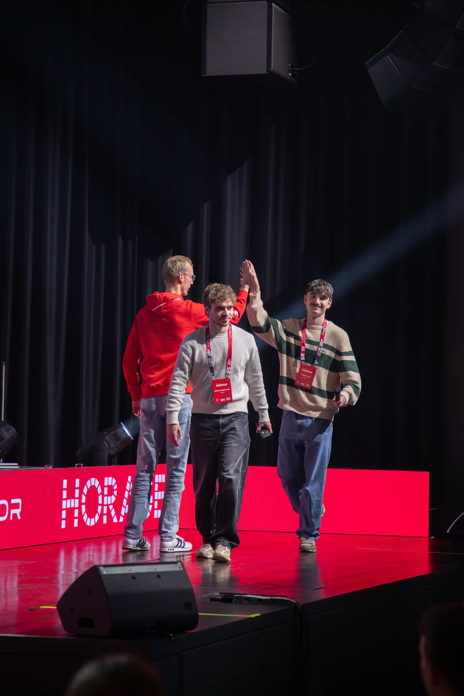 Two founders high-five the host as they walk on stage for their pitch